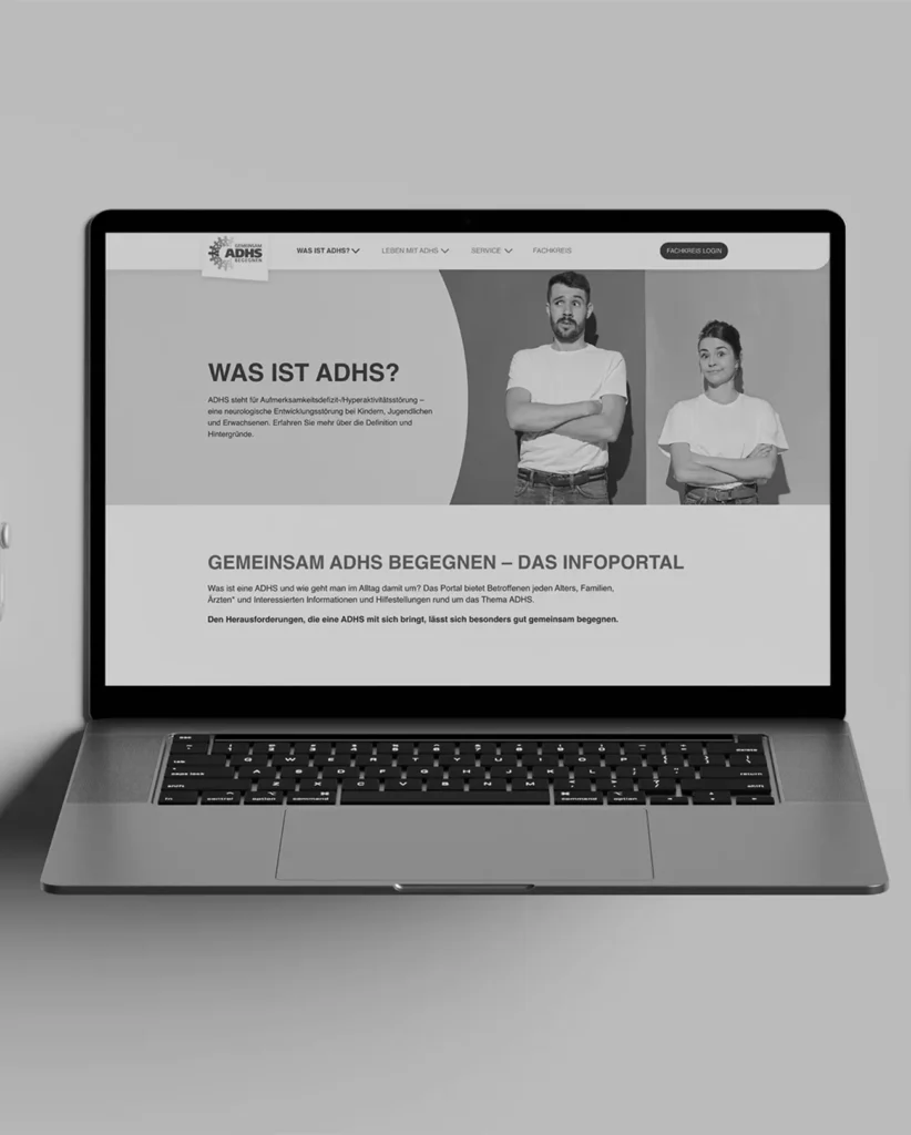 Ein Laptop zeigt eine Website mit der Überschrift „WAS IST ADHS?“. Zwei Personen stehen neben dem Text und blicken nach vorne. Die Seite befasst sich mit ADHS und bietet Informationen und Ressourcen. Das Design ist schwarz-weiß und schlicht.